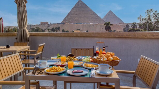 A table set with breakfast items and a view of the pyramids. - La Boutique Hôtel - Vue Des Pyramides (Giza)