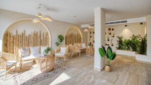 A spacious living area with wicker furniture, a patterned rug, and a wall decorated with vertical bamboo elements. - La Boutique Hôtel - Vue Des Pyramides (Giza)