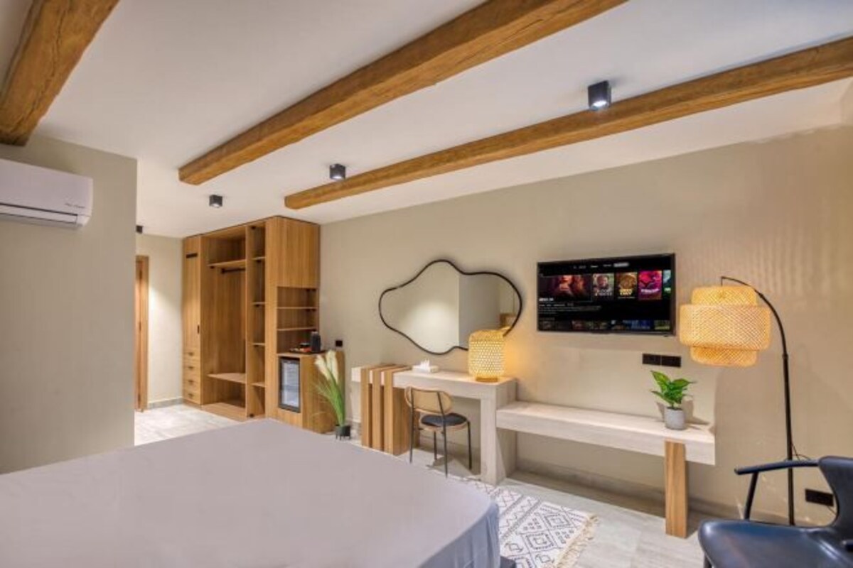 A bedroom with a bed, a desk, a chair, a TV, and a wardrobe.