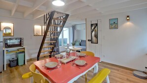 A dining area with a red table set for four, yellow chairs, a staircase, and a kitchen area with a built-in oven. - 1 bedroom nice apartment in Carolles (Carolles)