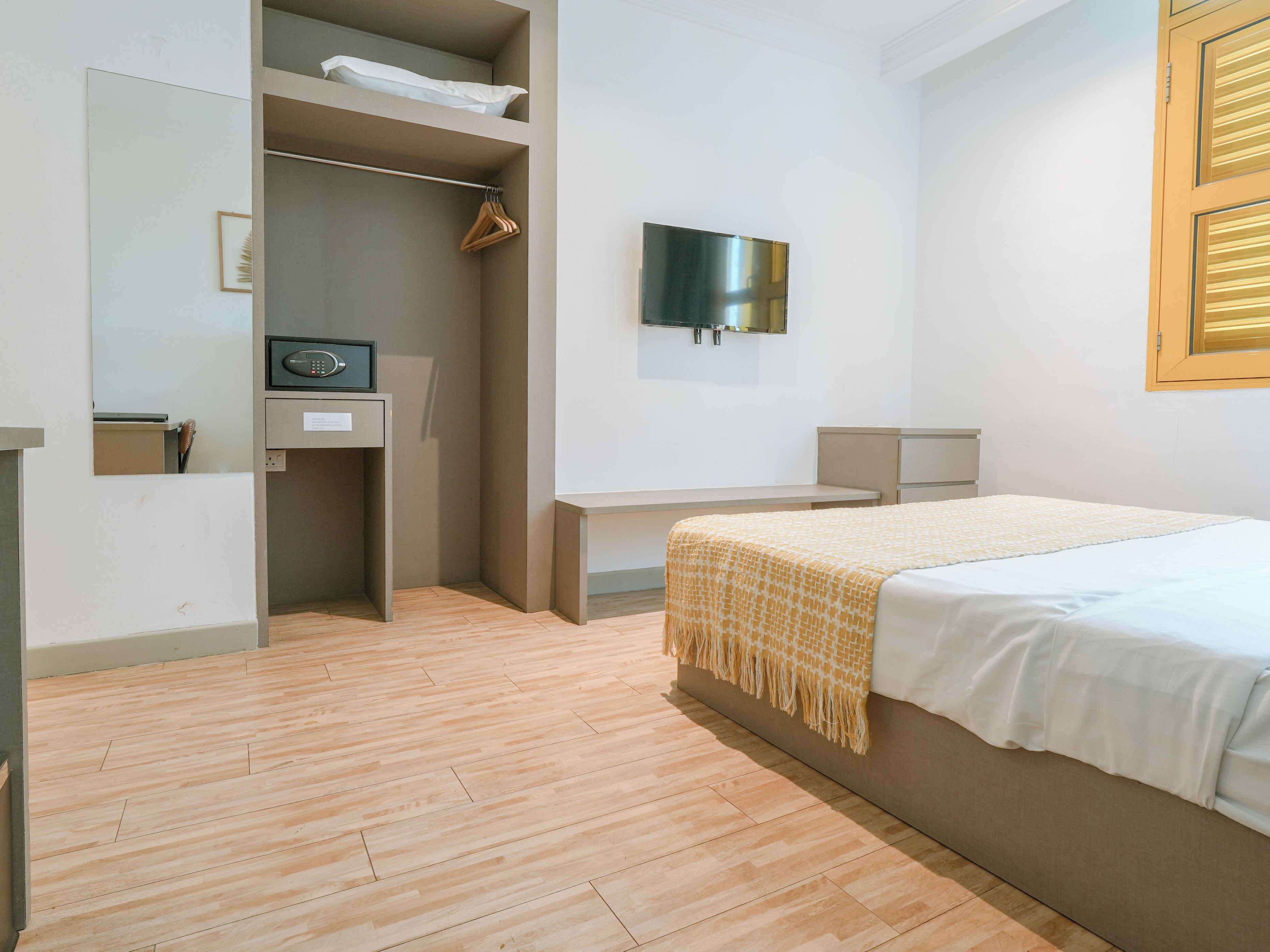 A hotel room with a bed, a desk, a wardrobe, and a television.