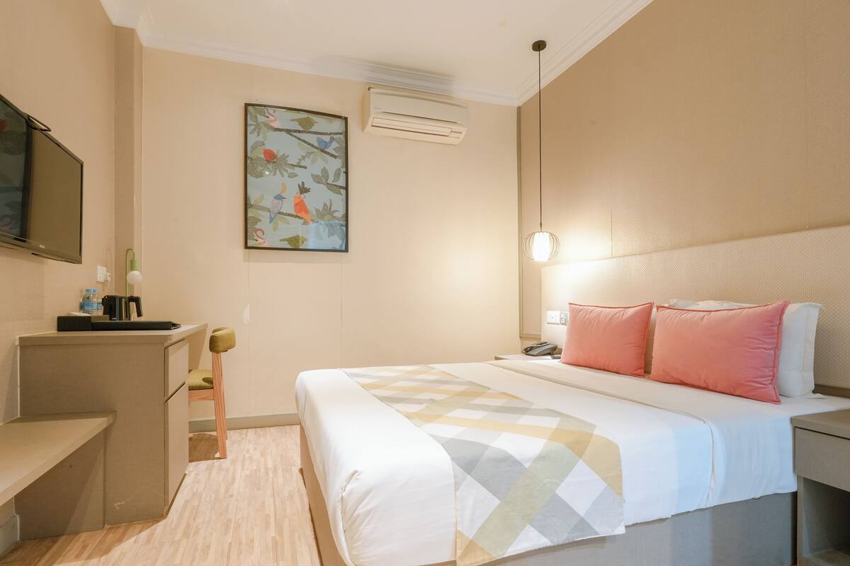 Ein Hotelzimmer mit Bett, Nachttisch, Lampe und einem Bild an der Wand.