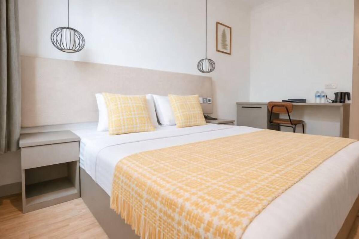 A hotel room with a bed, bedside tables, a desk, and a chair.