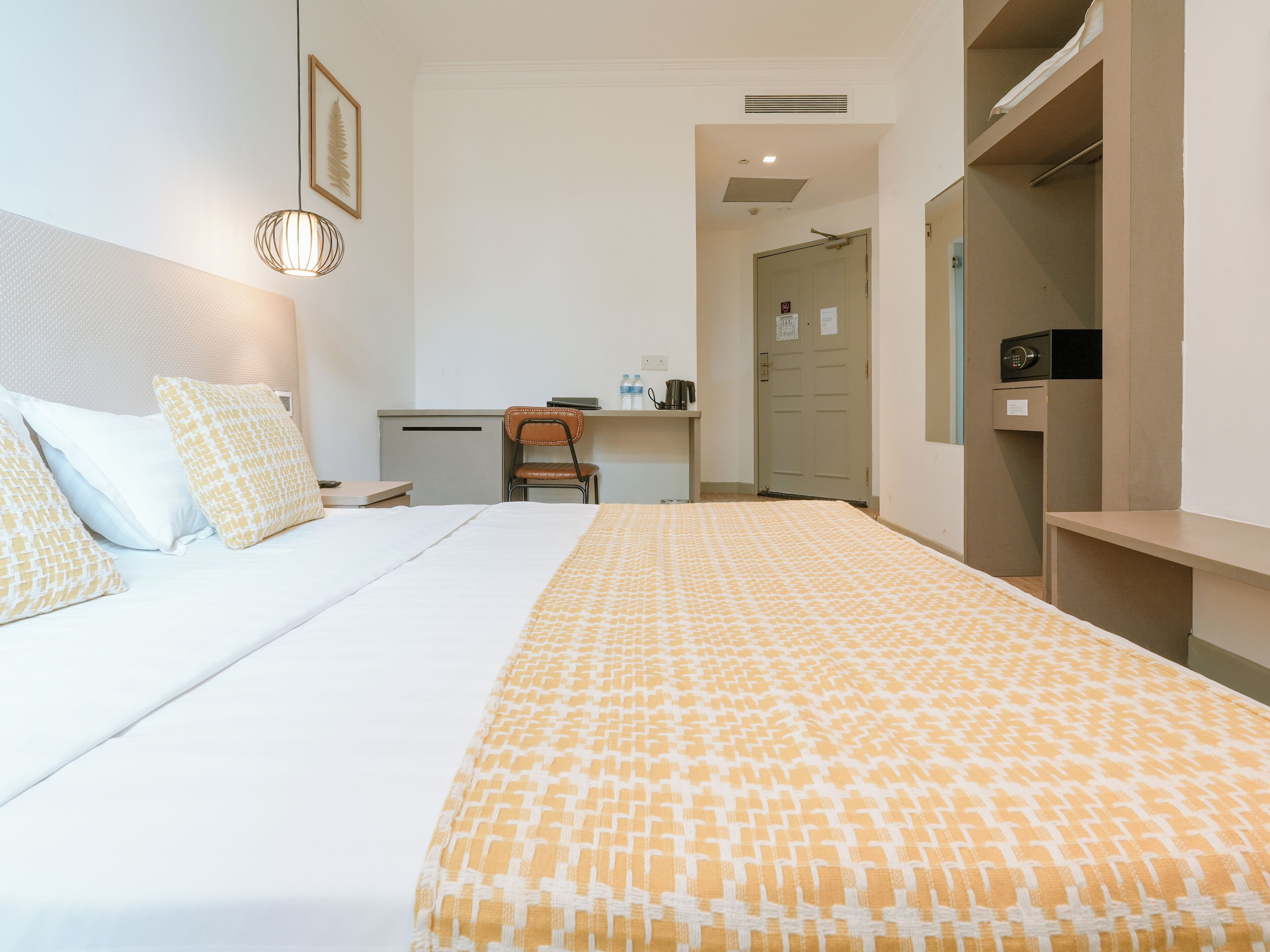 Een hotelkamer met een bed, een bureau, een stoel en een kledingkast.