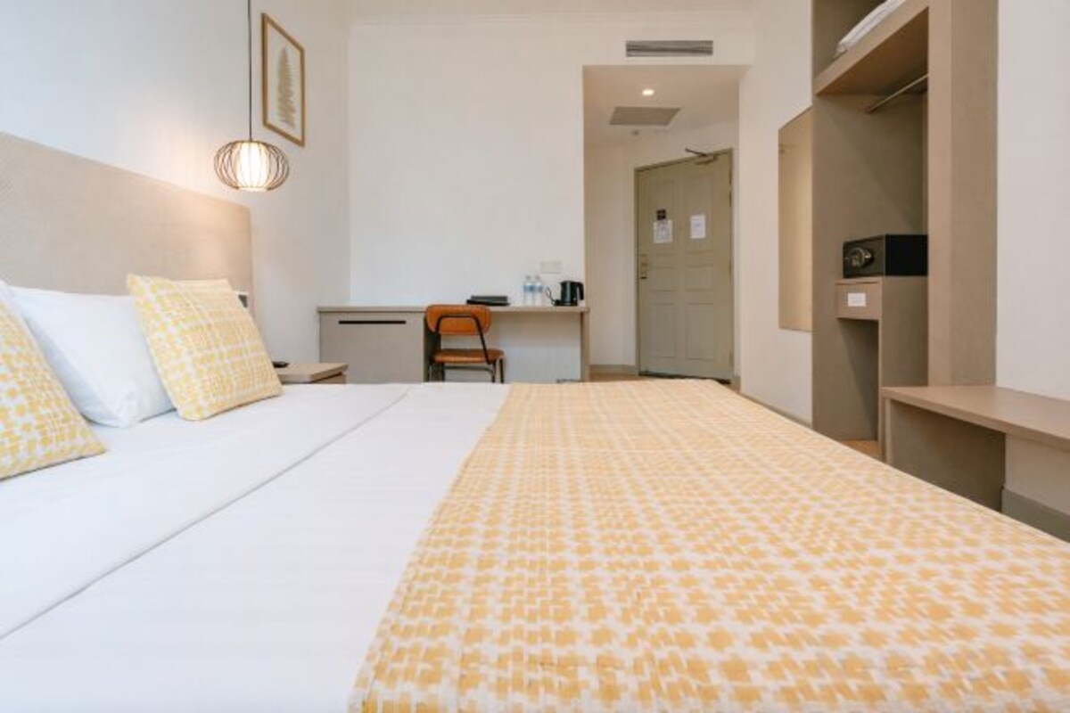 A hotel room with a bed, a desk, and a wardrobe.