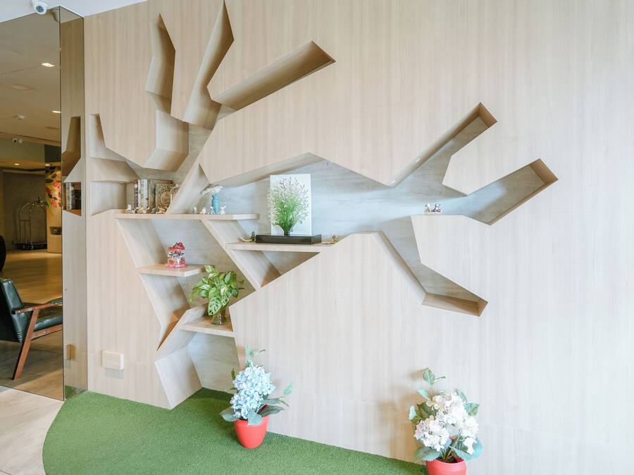 A modern interior with geometric wooden shelving units, green artificial turf, and potted plants.
