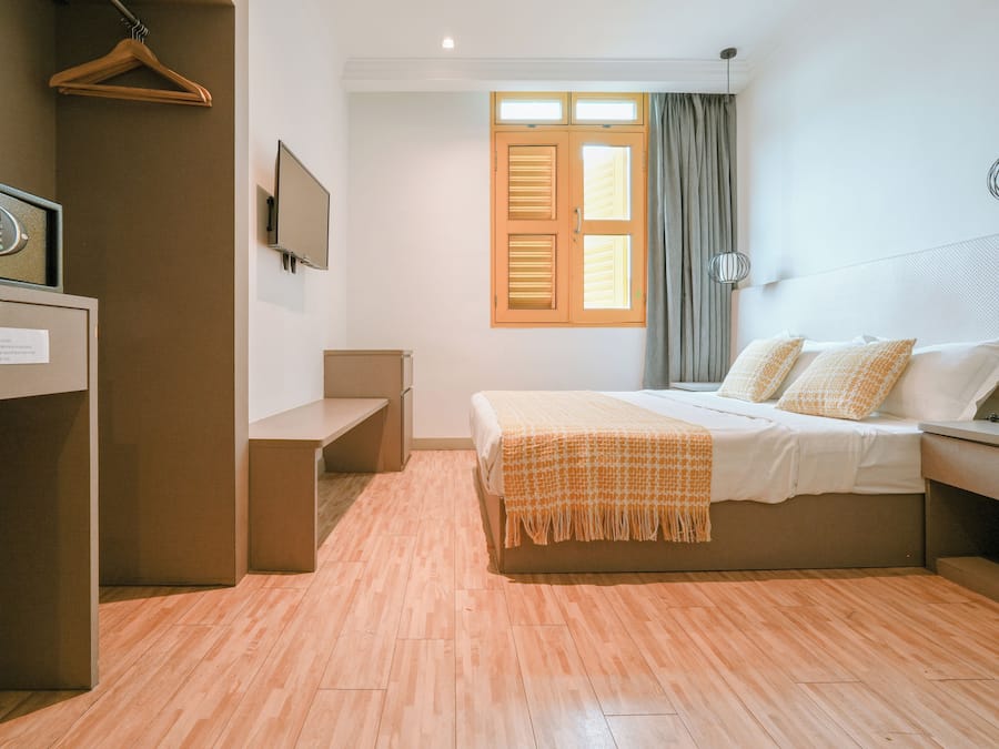 Een hotelkamer met een bed, een bureau, een stoel, een televisie en een raam met gordijnen.