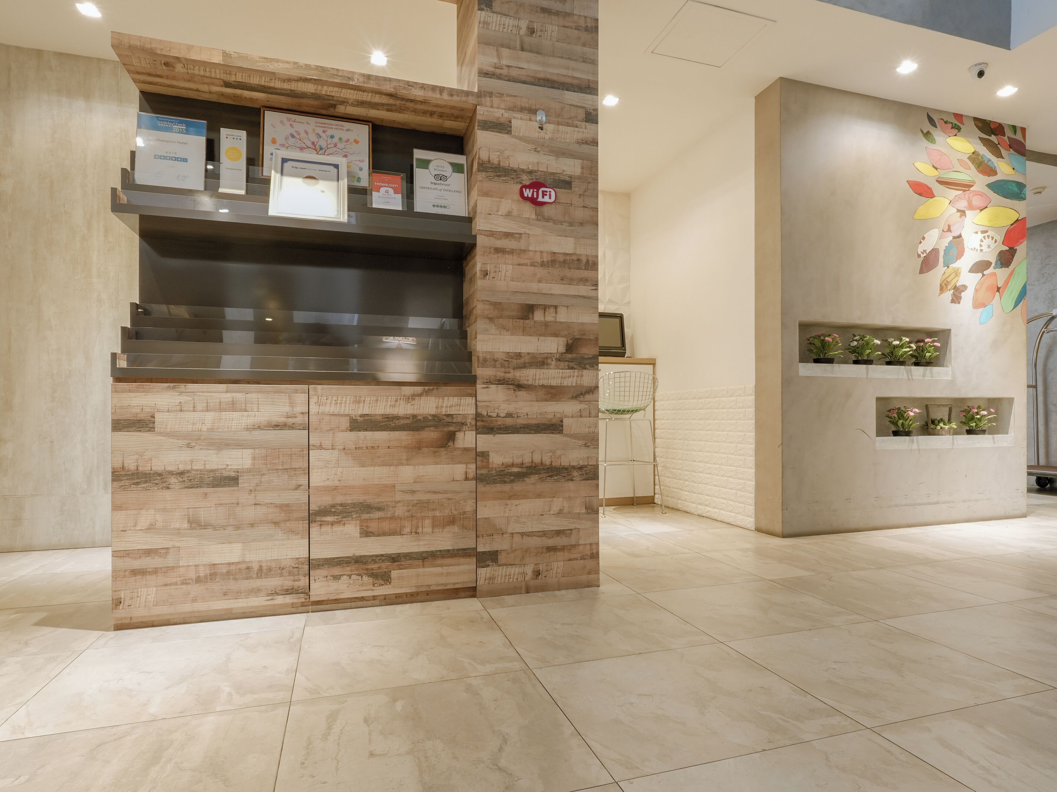 Un área de recepción con un mostrador de madera, una pantalla digital y un cartel de Wi-Fi en la pared.