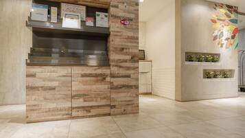 Un área de recepción con un mostrador de madera, una pantalla digital y un cartel de Wi-Fi en la pared.