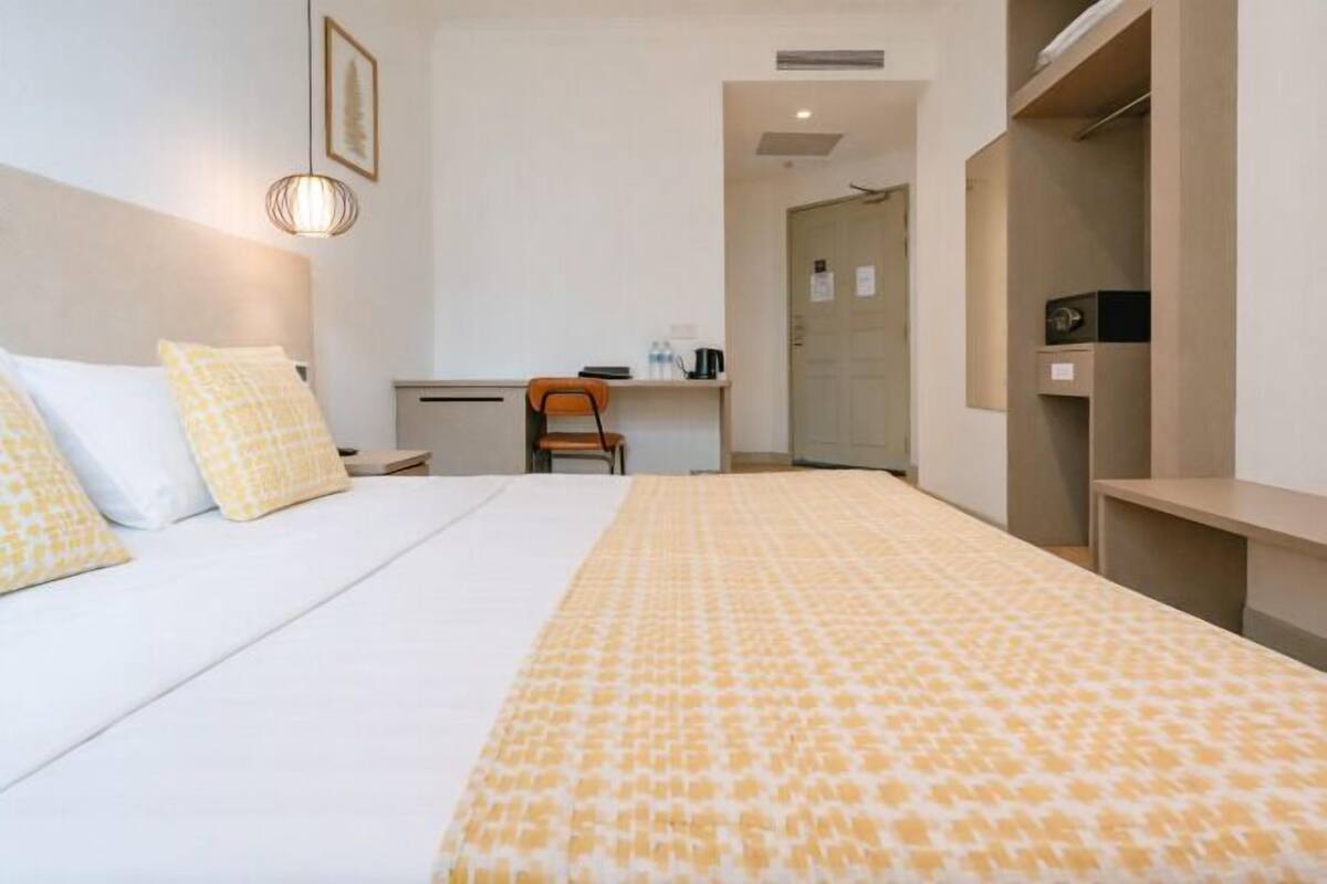 Ein Hotelzimmer mit Bett, Schreibtisch, Stuhl und Kleiderschrank.