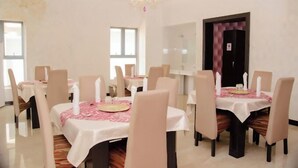 A dining area with round tables, chairs, and a chandelier. - Fancourt Hotel (Ilorin)
