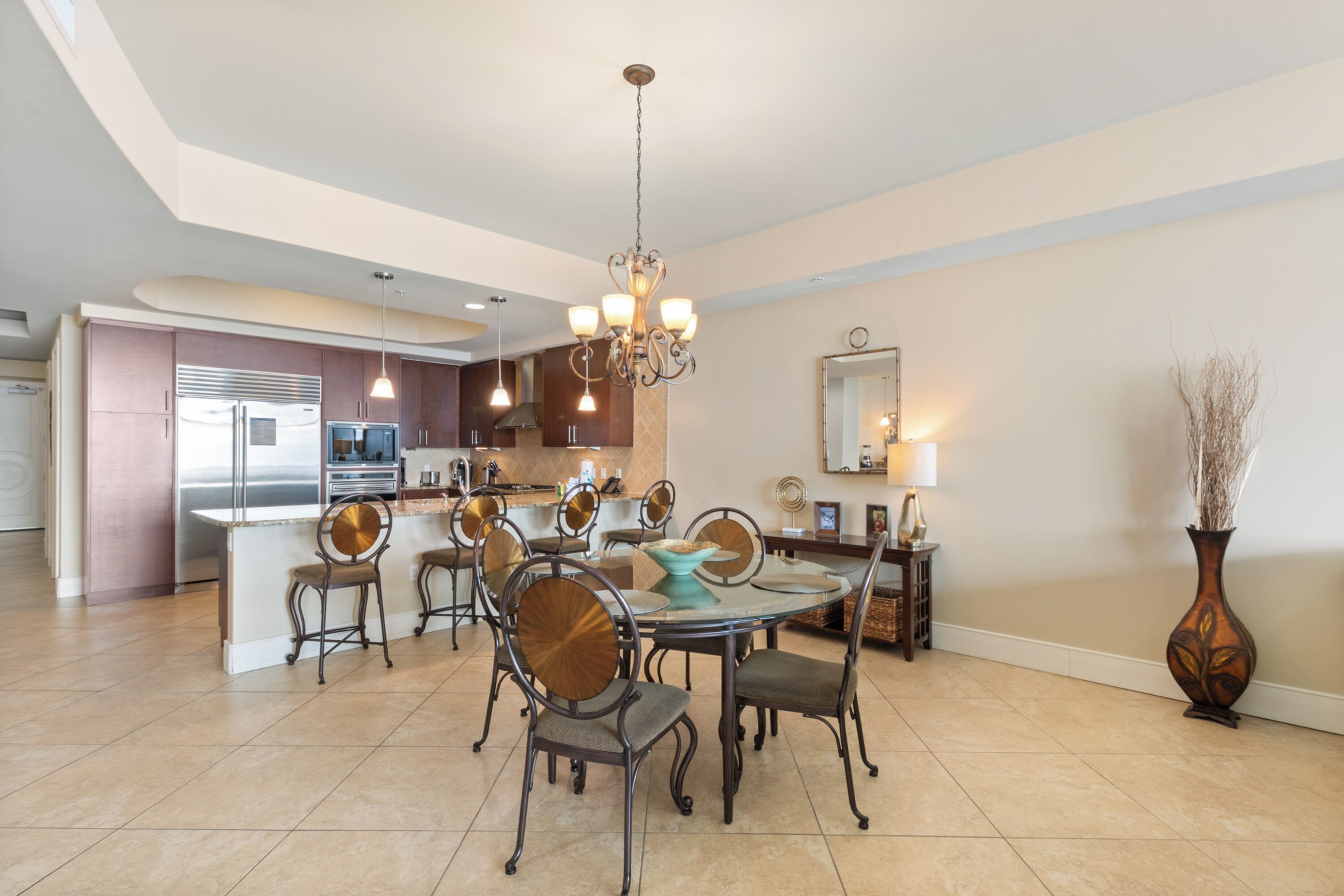 A modern kitchen with a central island, stainless steel appliances, and a chandelier.
