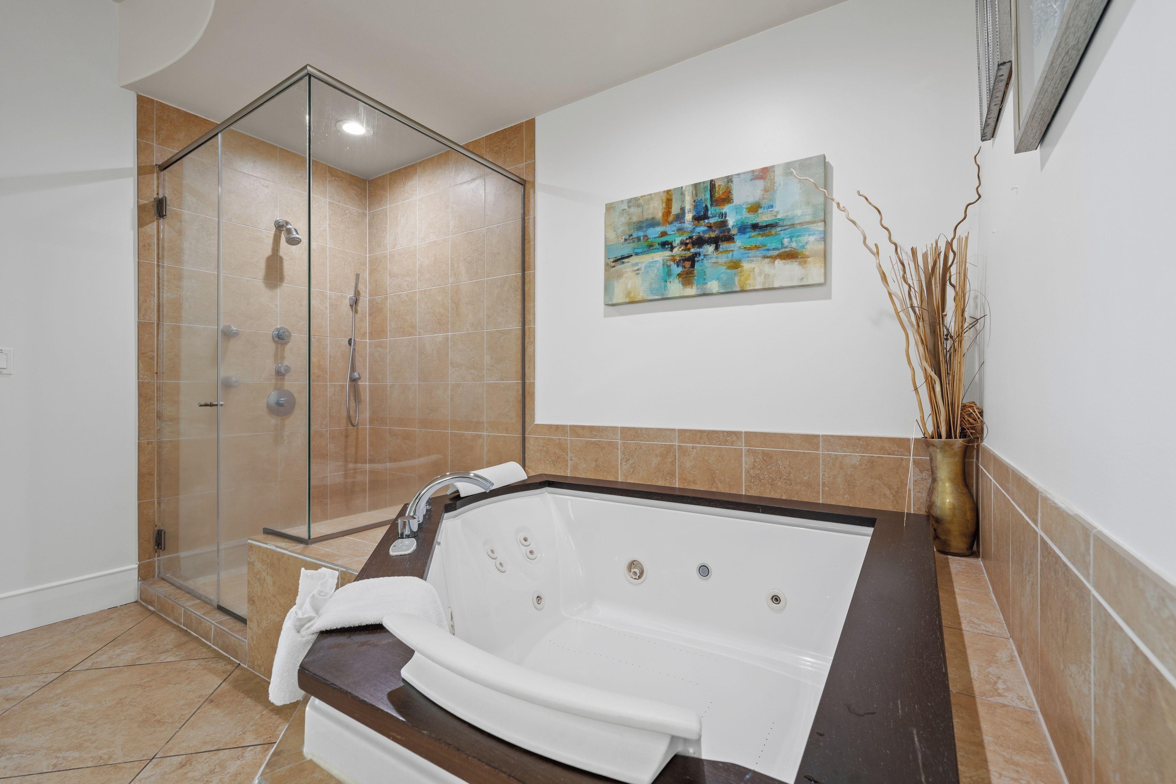Ein modernes Badezimmer mit einer Glasdusche, einer freistehenden Badewanne und einem Bild an der Wand.