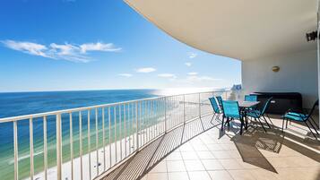 Een balkon met uitzicht op zee, een tafel met stoelen en een barbecue.