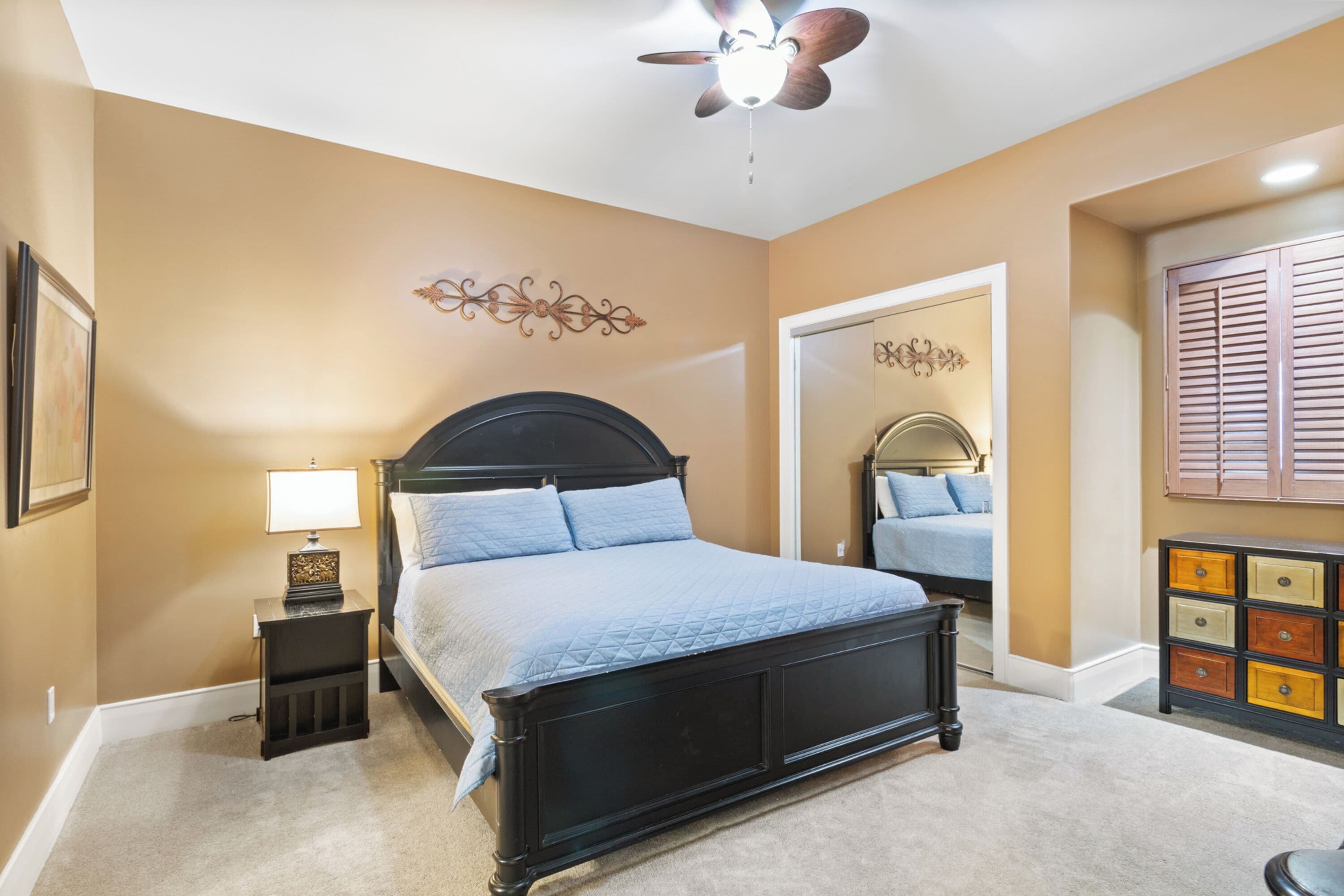 A bedroom with a bed, a nightstand, a dresser, and a ceiling fan.