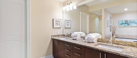 A bathroom with a large mirror, two sinks, and a vanity with drawers.