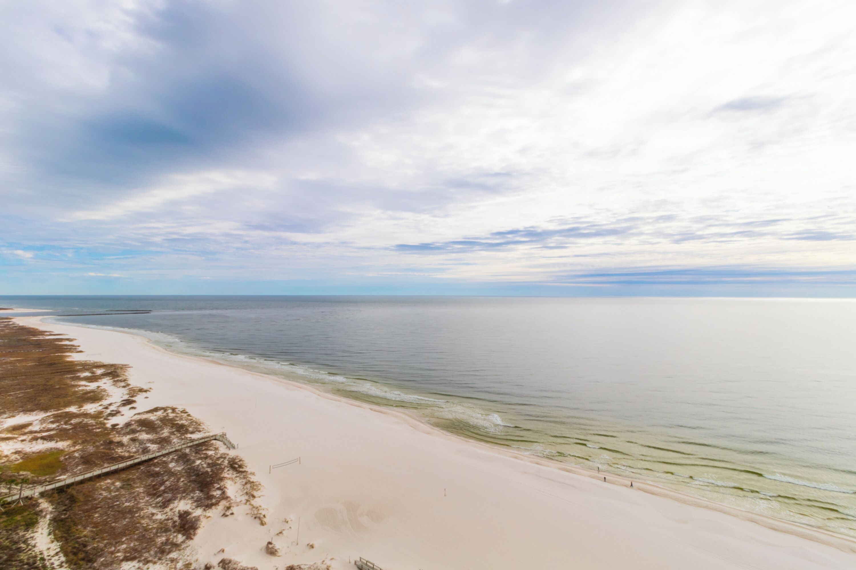 Ein Strand mit sandigem Ufer und ruhigem Wasser.
