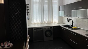 Una cocina compacta equipada con lavavajillas, lavadora y un lavamanos con grifo.