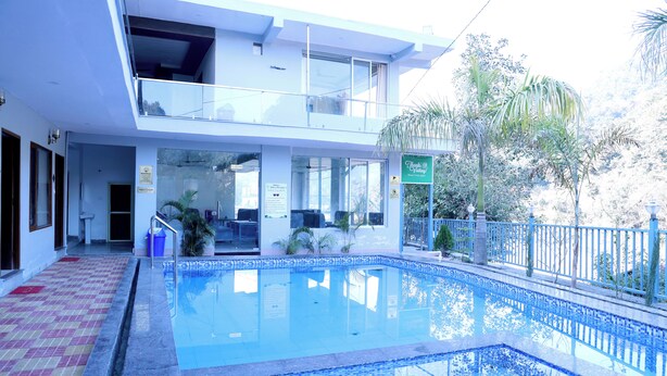 Un hotel con piscina, zona relax all'aperto coperta e un balcone.