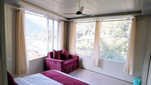 Una camera da letto con un letto, una sedia e ampie finestre.