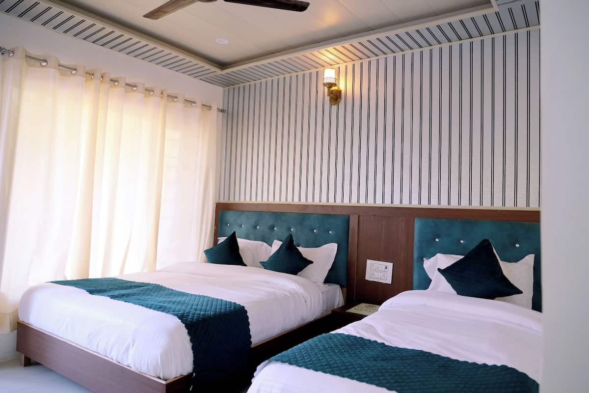Una habitación de hotel con dos camas, una pared a rayas y un ventilador de techo.