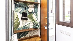 Una puerta de madera con un panel de vidrio, una bolsa de tela negra colgada de un gancho y una planta pequeña en un estante.