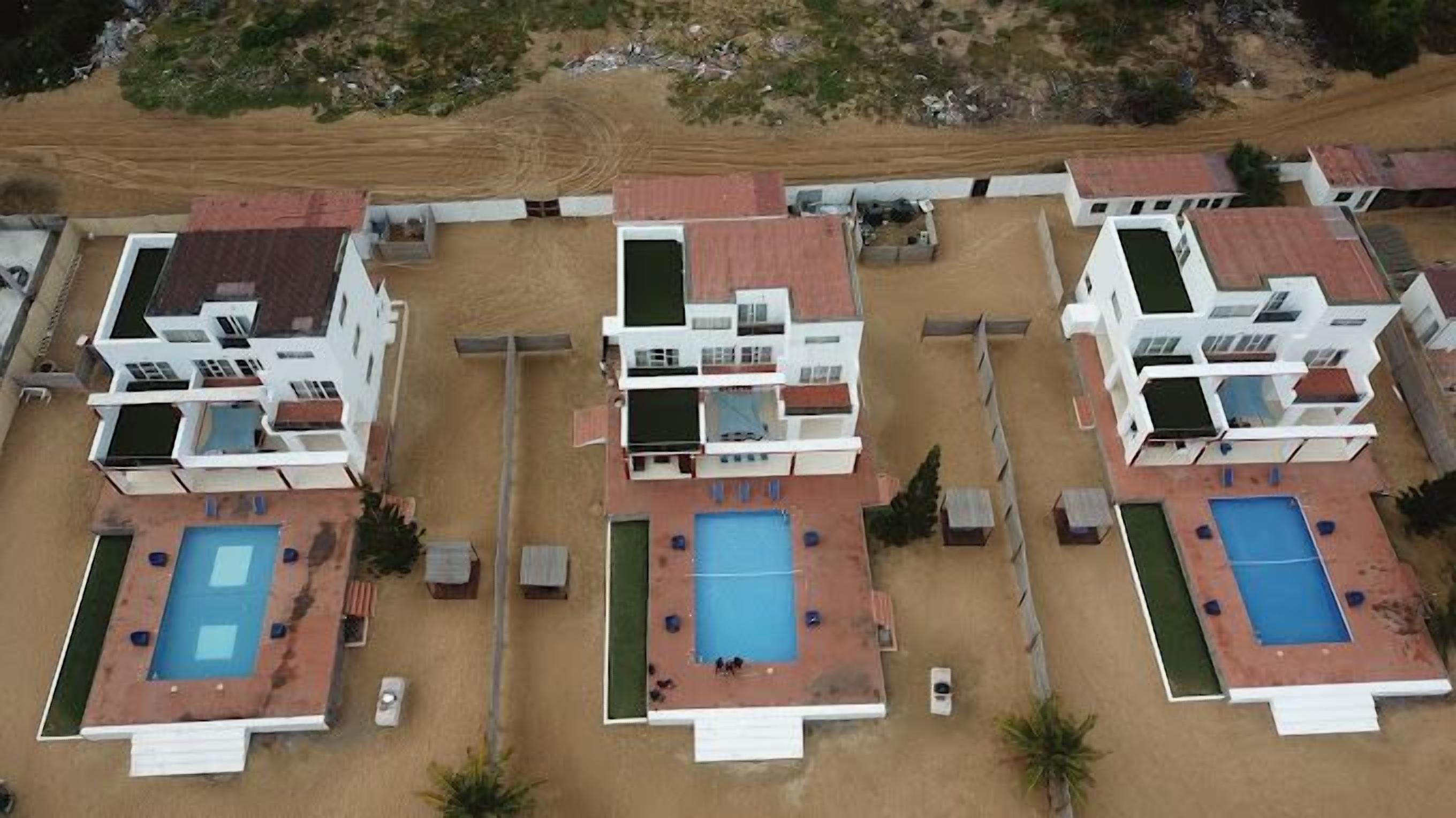 Ein modernes Resort mit drei Gebäuden, jedes mit einem Dachpool und einem zentralen Innenhof.