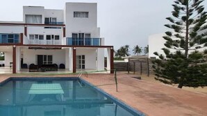 Una casa moderna de dos pisos amb una piscina al primer pla.