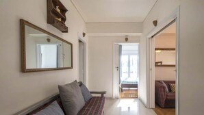Un pasillo con un banco, un espejo y una puerta que da a otra habitación.