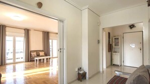 Un salón amplio con suelo de madera, un sofá, una mesita de centro y una puerta que da a otra habitación.