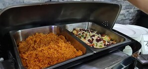 Un bufé con dos fuentes de comida: una de arroz anaranjado y otra con ensalada de frijoles y vegetales.