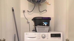 Une petite buanderie équipée d  ’un lave-linge à chargement frontal, d’un tuyau et d’un chauffe-eau.