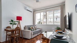 Una sala de estar moderna con comedor, un sofá, una mesa de centro y un televisor montado en la pared.