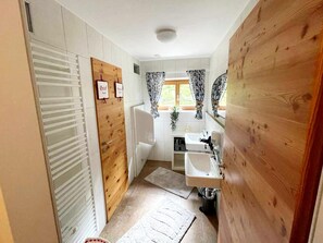 A compact bathroom with a wooden door, a white sink, and a shower.