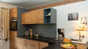 Una cocina compacta con armarios de madera, horno empotrado y cafetera sobre la encimera.