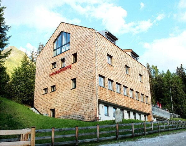 A multi-story building with a brick facade, large windows, and a sloped roof.