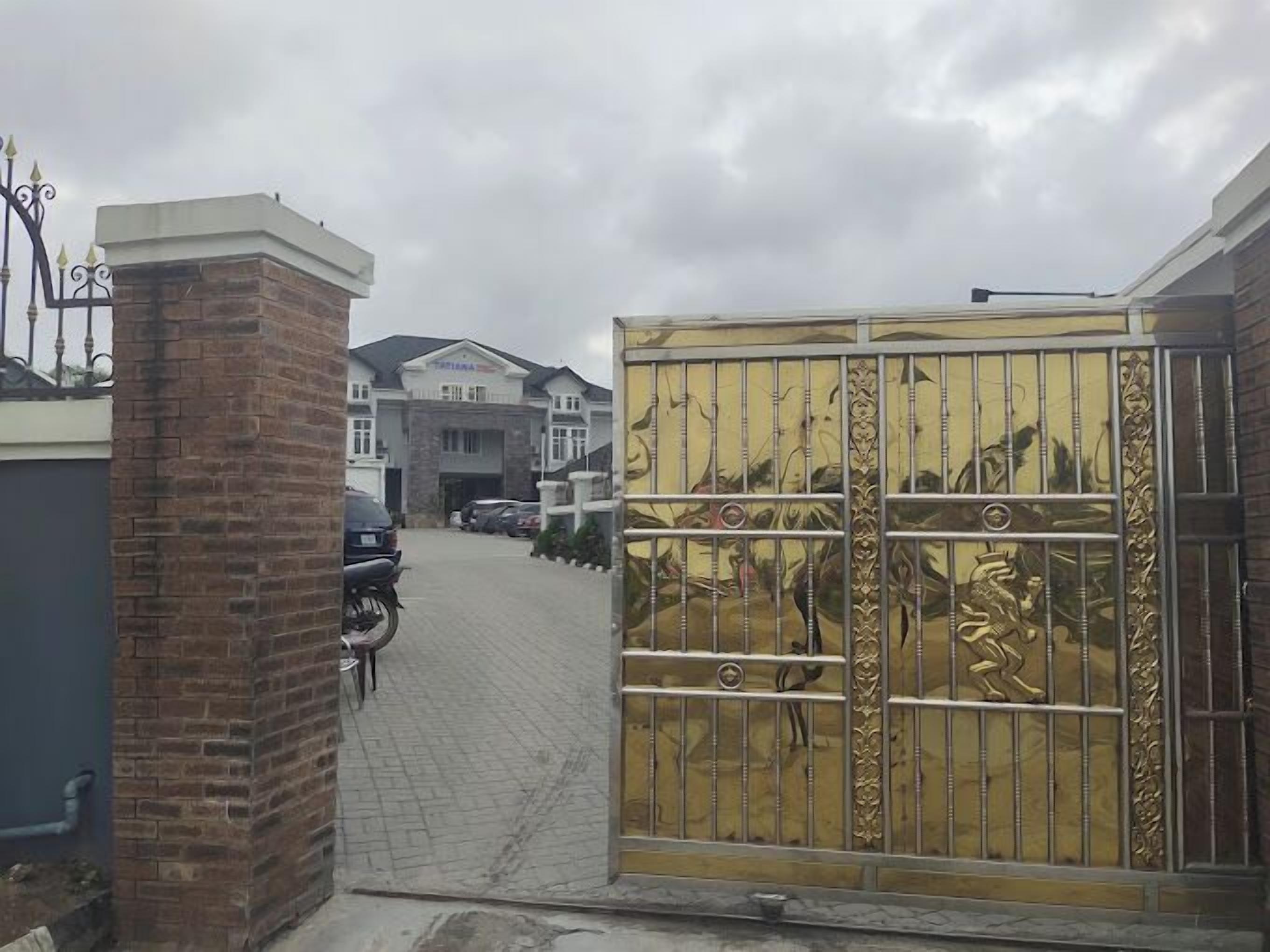 A gated entrance with a brick pillar and a metal gate with decorative elements.