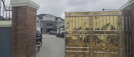 A gated entrance with a brick pillar and a metal gate with decorative elements.