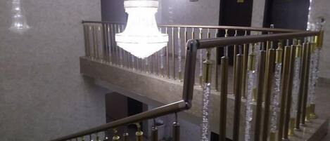 Una escalera con candelabro y barandales de metal.