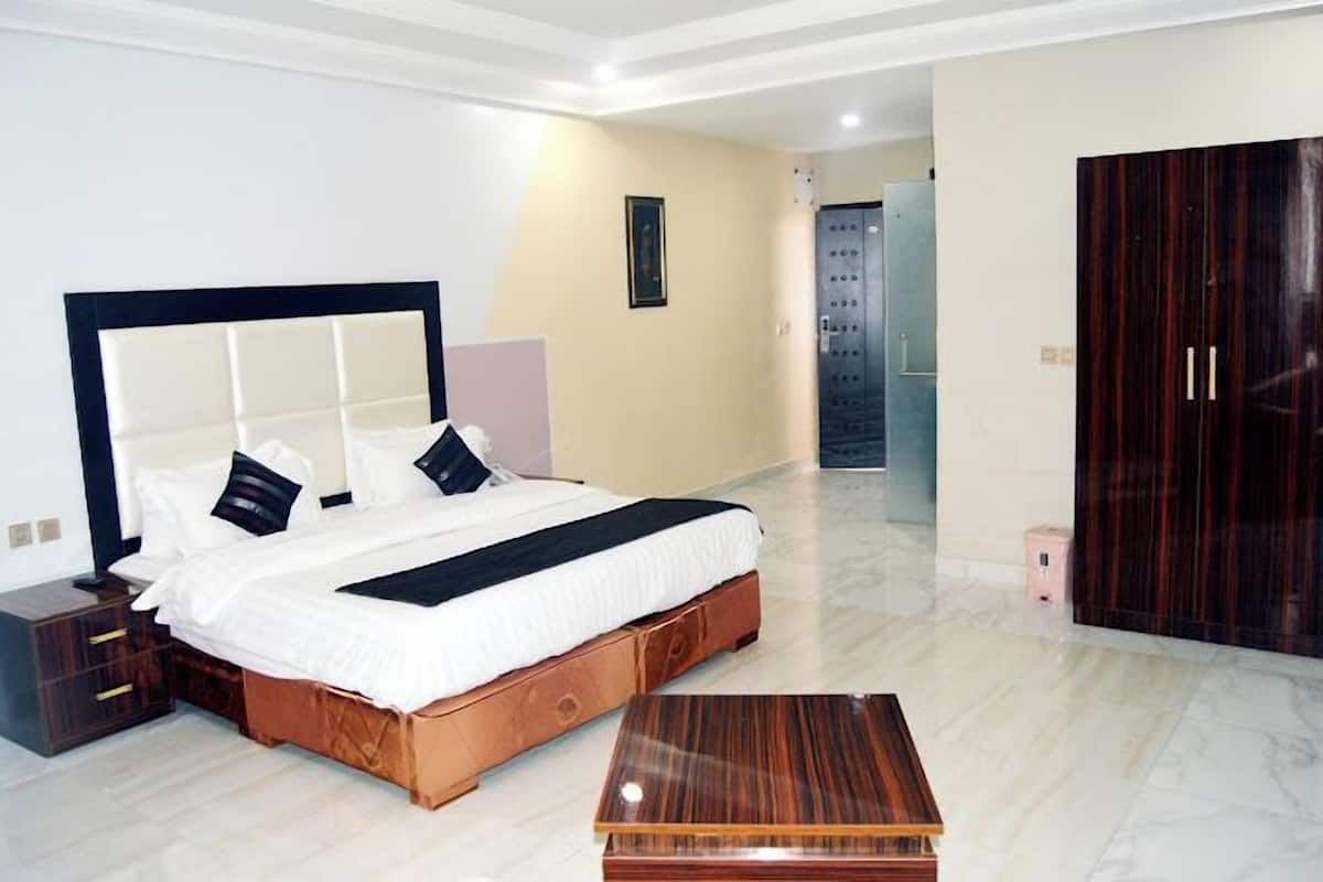 Quarto moderno com uma cama grande, mesa de cabeceira de madeira, um aparador, guarda-roupa e chão de mármore.