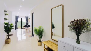 A modern hotel room with a large mirror, a wooden bench, a vanity with drawers, and potted plants. - MonHomestay Ha Long-Amazing view balcony (Hong Gai)