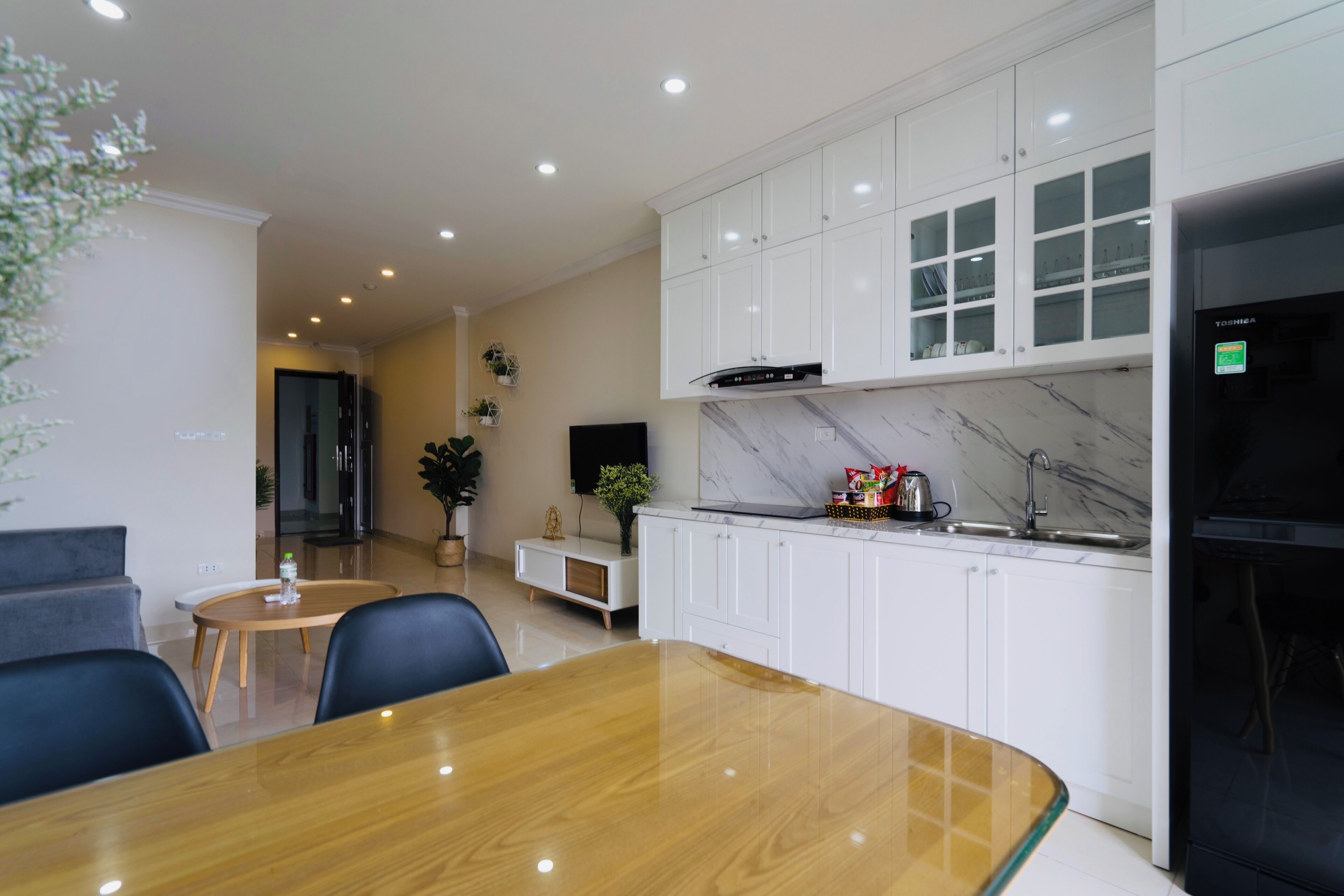 A modern kitchen with white cabinets, a marble backsplash, and a built-in oven.