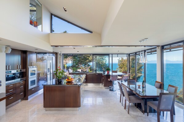 Una cocina moderna con una isla central, ventanas amplias y vista al mar.