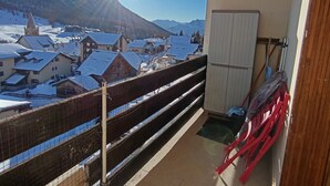 En balkon med udsigt over en snedækket landsby og bjerge.