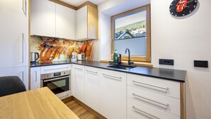 Una cocina moderna con armarios blancos, encimera negra y ventana con vistas a casas.