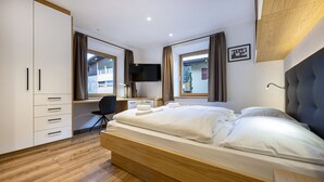 Una habitación de hotel moderna con una cama de madera, un escritorio, una silla y un televisor en la pared.