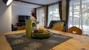 A dining table with a bowl of nuts and dried flowers, a green vase, and a black placemat with dandelion patterns. - 1002A Apartments No.7 Sella (Ortisei)
