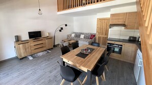 Un espacio habitable compacto con comedor, kitchenette y habitación en entrepiso.