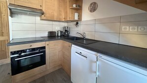 Una cocina moderna con gabinetes de madera, horno empotrado, lavavajillas y cafetera.