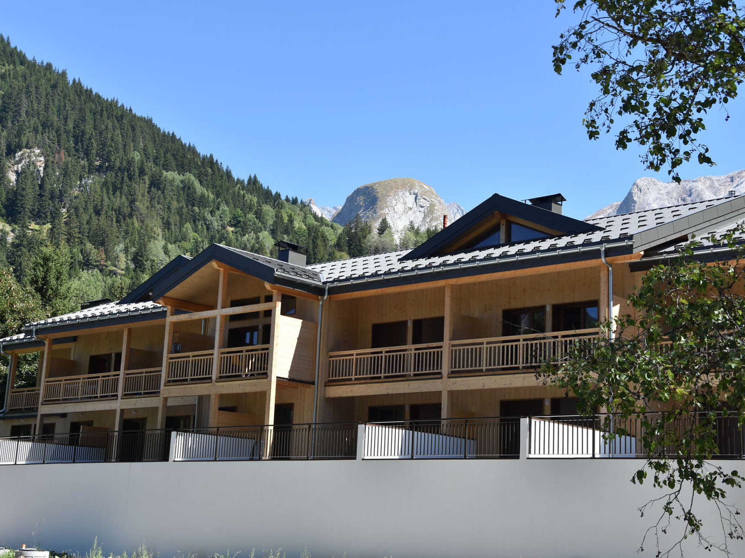 Un hotel de varios pisos con balcones y montañas al fondo.